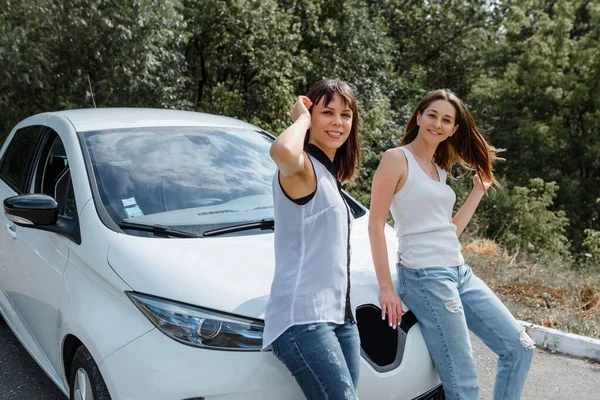 İki mutlu genç bayan arkadaş birbirleriyle konuşuyor ve arabada oturup arkadaşlığın tadını çıkarıyorlar. Arkadaş kavramınla seyahat et.