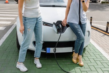 Güç kablosu tutan ellerini kapat ve elektrikli arabanın aküsünü şarj et. Çevre dostu araba, şarj istasyonunda elektrikli araba aküsü şarj ediliyor. Çevre taşımacılığı kavramı