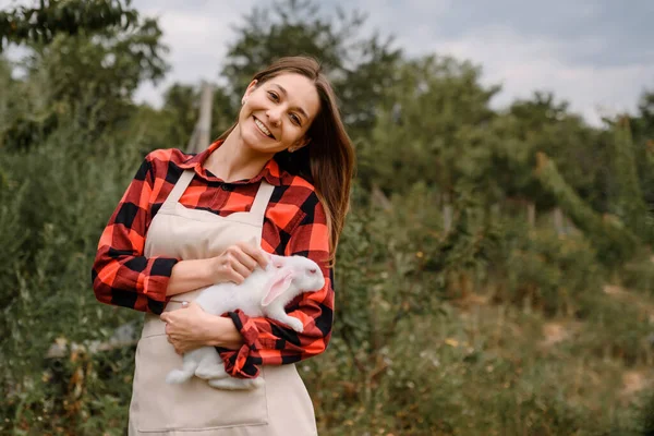 Fiatal Boldog Mosolygó Női Farmer Kamerába Néz Egy Fehér Nyulat — Stock Fotó