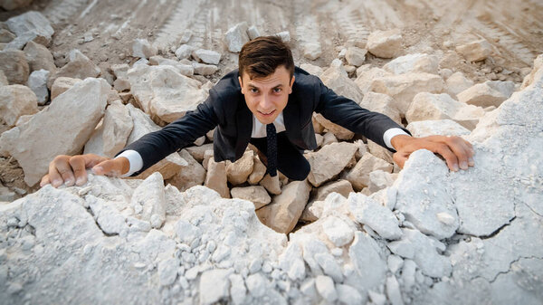 Портрет бизнесмена в классической куртке и галстуке, который поднимается на гору. Концепция бизнеса, находящегося в состоянии финансового кризиса