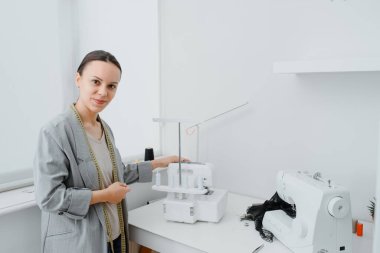 In the tailoring workshop concept. Portrait of happy smiling young woman tailor needle woman looking to the camera.