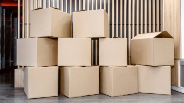 Bir ofiste gönderilmeye hazır bir sürü karton kutu var.
