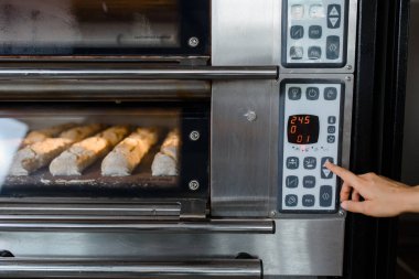 Fırıncının elini kapayarak elektrikli fırını aç ve fırında ekmek pişirmek için ekmek imalat fabrikası Fransız baget ekmeği fabrikası konsepti var..