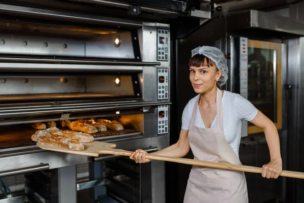 Szczęśliwy Uśmiechnięty Młody Biały Kobieta Piekarz Zdejmuje Piekarnika Francuski Chleb — Zdjęcie stockowe
