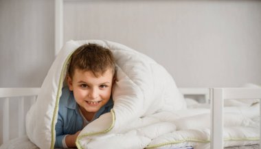 Küçük çocuk yatağında yatıyor ve gülümsüyor. Çocukluk kavramı