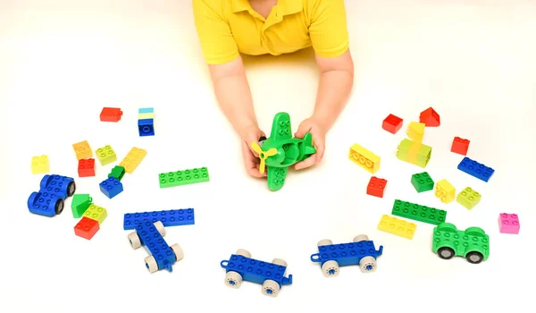 白い背景におもちゃの飛行機やおもちゃのレンガで遊んでいる子供の男の子の手を閉じます テキストのスペースをコピー ストック画像