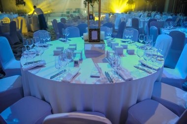 Düğün resepsiyonu parti masası. Kırmızı şakayık ve güllerle süslenmiş şarap kadehleri. Çatallar, bıçaklar, tabaklar