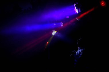 Sahnede bir şarkıcının karanlık siluetinin olduğu bir gece partisi. Parlak çok renkli ışıkları olan arkaplan