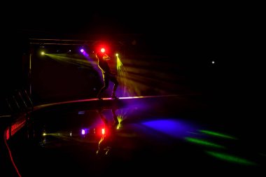 Sahnede bir şarkıcının karanlık siluetiyle havuz partisi. Parlak çok renkli ışıkları olan bir arka plan. Bir müzik grubu konseri.