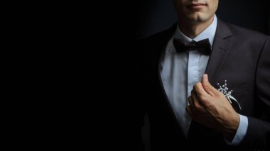 Siyah takım elbiseli, beyaz gömlekli, stüdyoda poz veren, siyah arka planda izole genç bir manken. İş adamı portresi. Düğünde damat. Uzayı kopyala Yatay görünüm.