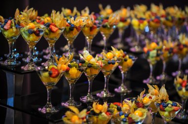 Düğün süsleme ziyafetinde bir stantta bir sürü farklı meyve var: portakal, kivi, fisali, çilek ve mavi kızılcık.