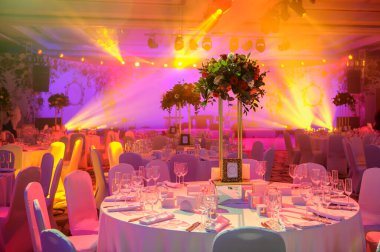 Düğün resepsiyonu masası pembe şakayık ve güllerle süslenmiş. Şarap bardakları, çatallar, bıçaklar, tabaklar