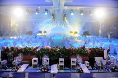 Düğün resepsiyonu parti masası. Kırmızı şakayık ve güllerle süslenmiş şarap kadehleri. Çatal ve bıçaklar.