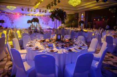 Düğün resepsiyonu parti masası. Kırmızı şakayık ve güllerle süslenmiş şarap kadehleri. Çatallar, bıçaklar, tabaklar