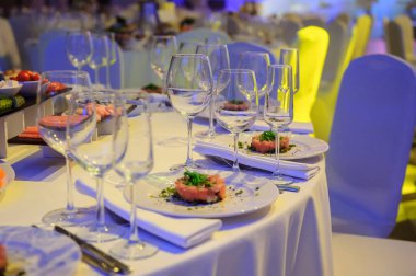 Düğün masası resepsiyonunda şarap bardakları ve somon tartarlı tabaklar.