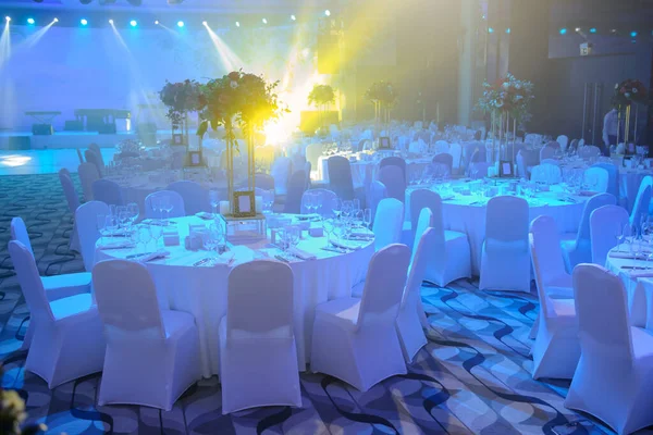 Düğün resepsiyonu parti masası. Kırmızı şakayık ve güllerle süslenmiş şarap kadehleri. Çatallar, bıçaklar, tabaklar