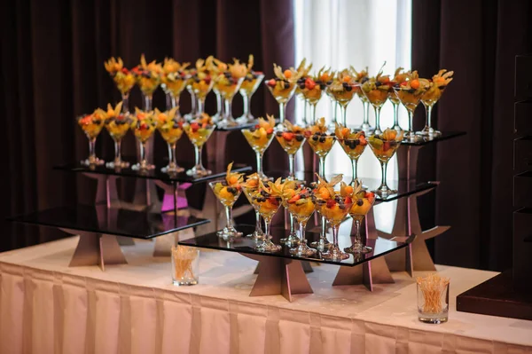 Düğün süsleme ziyafetinde bir stantta bir sürü farklı meyve var: portakal, kivi, fisali, çilek ve mavi kızılcık.