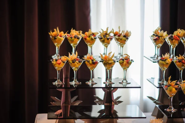 Düğün süsleme ziyafetinde bir stantta bir sürü farklı meyve var: portakal, kivi, fisali, çilek ve mavi kızılcık.