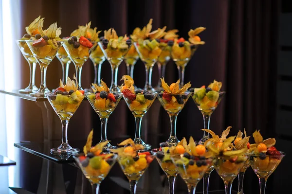 Düğün süsleme ziyafetinde bir stantta bir sürü farklı meyve var: portakal, kivi, fisali, çilek ve mavi kızılcık.