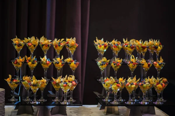 Düğün süsleme ziyafetinde bir stantta bir sürü farklı meyve var: portakal, kivi, fisali, çilek ve mavi kızılcık.