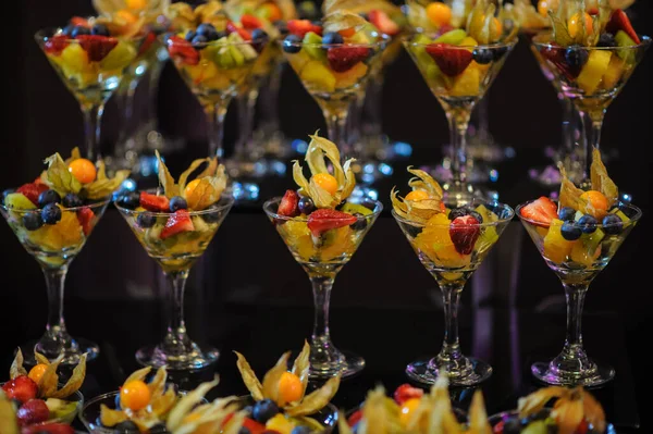 Düğün süsleme ziyafetinde bir stantta bir sürü farklı meyve var: portakal, kivi, fisali, çilek ve mavi kızılcık.