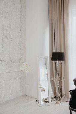 Ayna, lamba ve çiçeklerle dekore edilmiş bir odanın köşesini kapat.