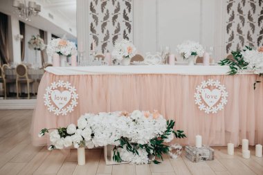 Düğün masasını beyaz çiçeklerle süsleyin şakayık ve güllerle, ahşap harflerle, Bay & Bayan aşık, mumlarla.