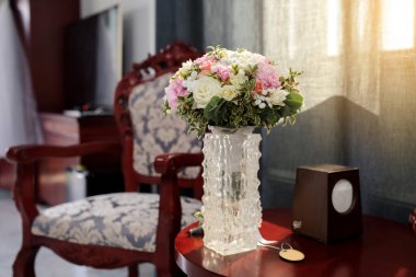 Gelin çiçeğini kapat. Masanın üstünde gül buketi. Eski bir otel odasında, eski bir sandalye, masa ve gelinlik ayakkabısı var.