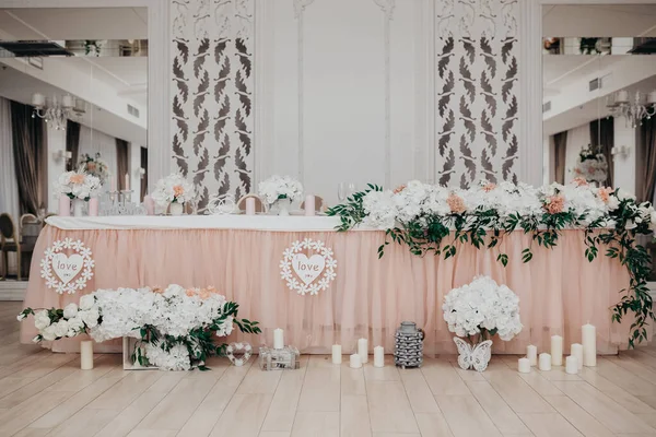 Düğün masasını beyaz çiçeklerle süsleyin şakayık ve güllerle, ahşap harflerle, Bay & Bayan aşık, mumlarla.