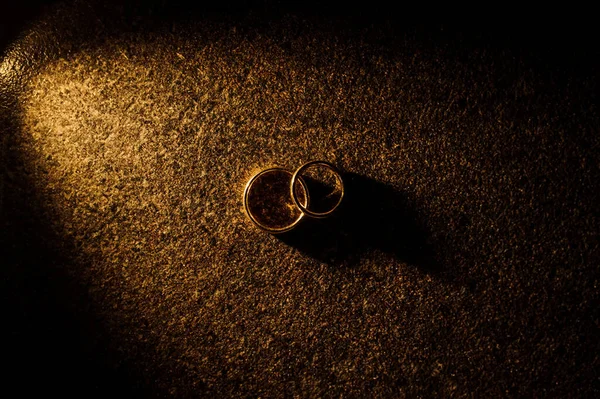 Gelin ve damadın iki alyansını karanlık arka planda fotokopi alanı ve metin ve logo ile kapatın.