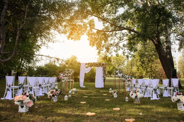 Park / Orman 'da bir düğün hazırlığı. Ahşap kemer ve sandalyeler beyaz ve pembe çiçeklerle süslenir güller ve şakayıklar, yerde mumlarla süslenir..  