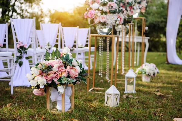 Park / Orman 'da bir düğün hazırlığı. Ahşap kemer ve sandalyeler beyaz ve pembe çiçeklerle süslenir güller ve şakayıklar, yerde mumlarla süslenir..  