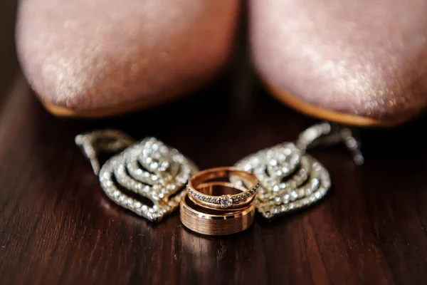 用粉红的女鞋把结婚戒指贴在木桌上 — 图库照片