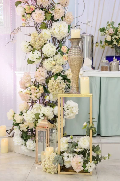 Düğün partisi fotoğraf kabini bölgesi vazolarda beyaz güllerle süslenmiş.