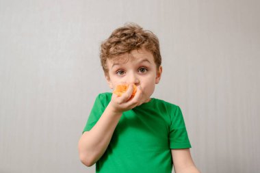 Çocuklar obezite konsepti. Gri arka plandaki yeşil tişörtlü çocuk çok fazla kızarmış patates cipsi yiyor. Çocuk obezitesi üreten yiyecekler