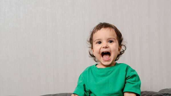 Little girl kid in green t-shirt a laughing and smile on gray background