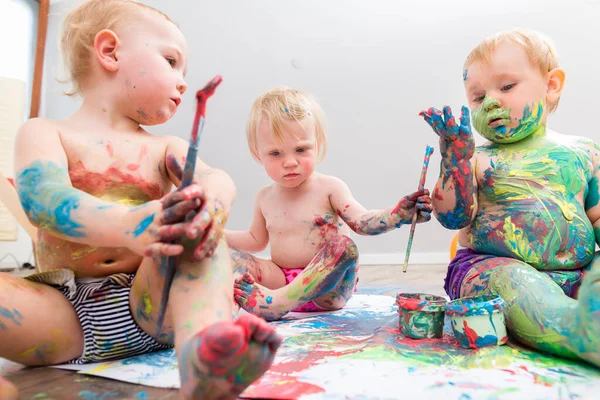 Trois bébés mignons jouant avec une couleur vibrante — Photo