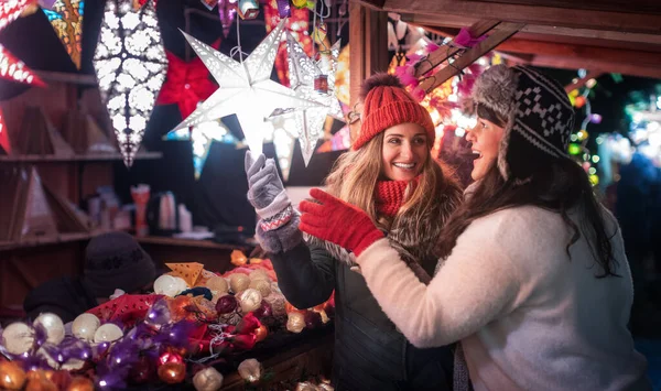 Двоє друзів купують різдвяні прикраси на зимовому ринку — стокове фото