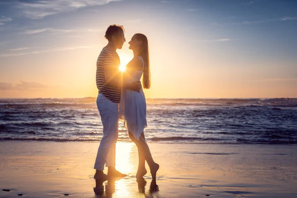 Romantiskt par kär kyssas på stranden under solnedgången — Stockfoto