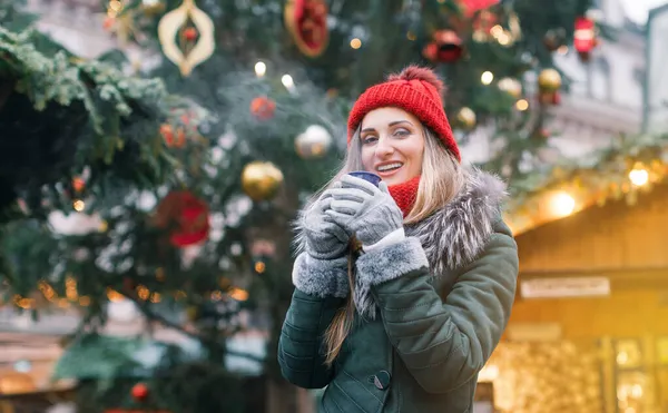 Schöne Frau trinkt Glühwein auf Weihnachtsmarkt — Stockfoto