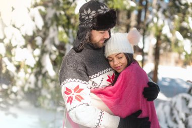 Birbirine aşık romantik çiftler kış ormanlarında birbirlerine sarılıyorlar.