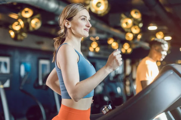 Beautiful woman exercising on treadmill in gym — Stock Photo, Image