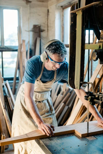 Charpentier sur la scie à ruban dans son atelier de bois — Photo