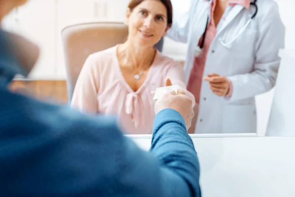 Paciente que da tarjeta sanitaria electrónica en recepción del consultorio médico — Foto de Stock