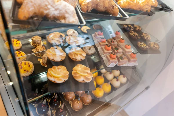 Confectioner shot through glass display in her shop — Stock Photo, Image