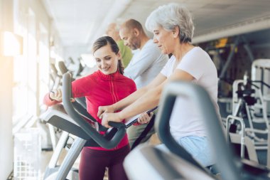 Spor salonunda beden eğitimi koçu son sınıflara yardım ediyor.