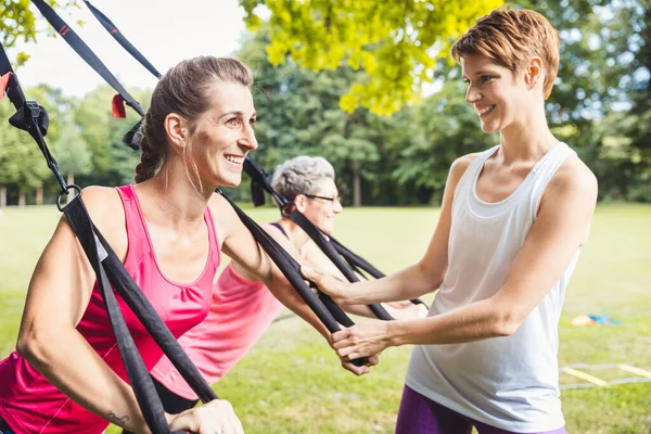 Sonriendo ejercicios de mujer joven usando entrenamiento de suspensión — Foto de Stock