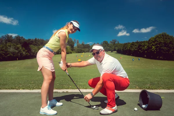 Golf pro onderwijs een vrouw student van de driving range — Stockfoto