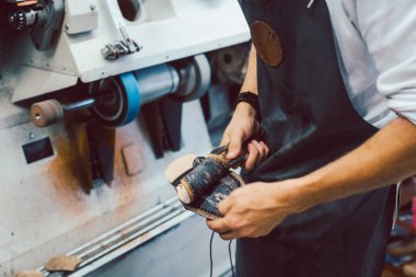 Makineli bir çift ayakkabı üzerinde çalışan ayakkabıcıya yakın plan.