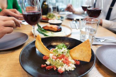Önünde guacamole olan insanların olduğu şık bir restoranda bir tabak güzel yemek.